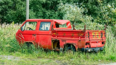Çimlerle kaplı eski kırmızı bir araba.
