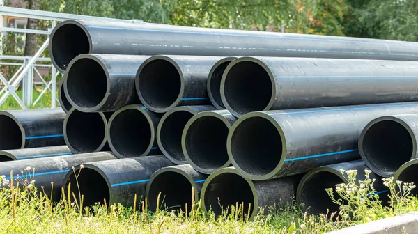 black sewer pipes on the construction site are stacked on top of each other