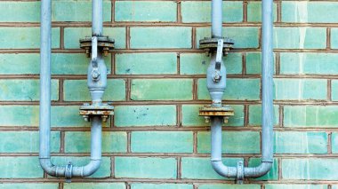 Yeşil tuğla duvarda gaz tedarik prizleri olan boru hattı