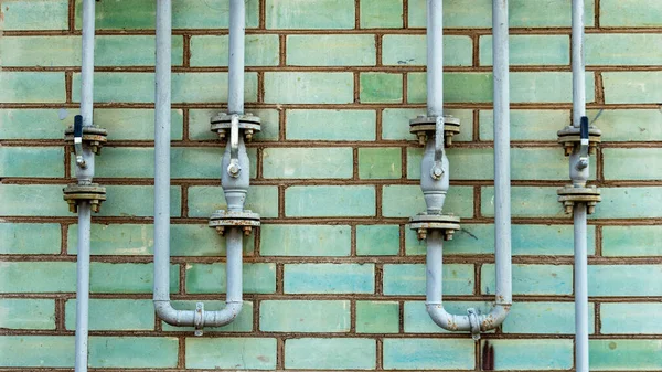 Yeşil tuğla duvarda gaz tedarik prizleri olan boru hattı