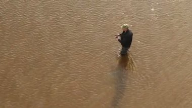 Bir balıkçı suda durur ve balık yakalar.