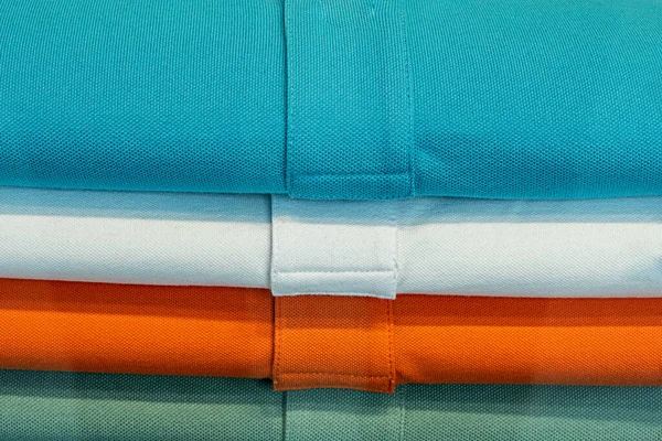 blue, white, orange and green colored shirts in a heap