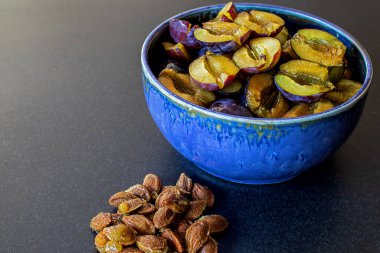 Ev yapımı seramik kasede bir yığın sulu erik. Mutfak tezgahında duran taşlar.