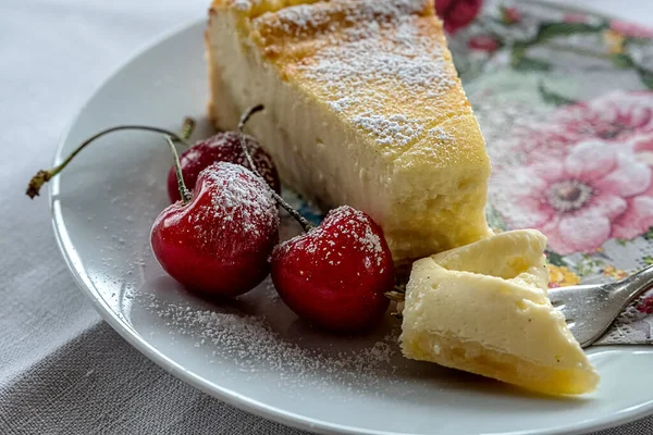 ホワイトプレートにチーズケーキとチェリー 花模様のナプキン — ストック写真