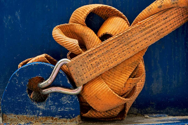close up of a sturdy nylon strap attached to a blue machine with a steel hook