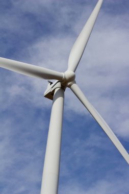 Mavi gökyüzü arka planına sahip dev bir rüzgar güç türbininin pervane pervanelerinin yukarı doğru görüntüsünü kapat