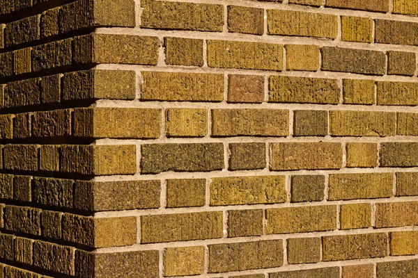 Vintage brown corner brick wall background with textured bricks with a hint of green color