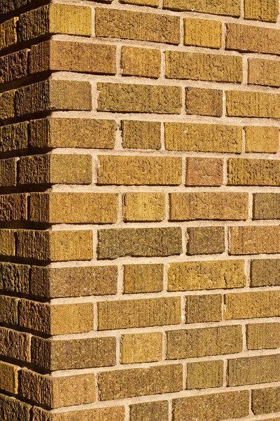 Vintage brown corner brick wall background with textured bricks with a hint of green color