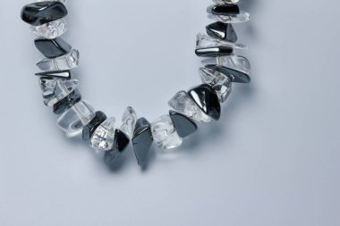 Close up abstract view of a vintage polished black hematite and clear quartz stone necklace on a white background with copy space