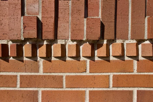 Brick wall texture background with modern traditional clay bricks adorned with accent rows of geometric design protruding bricks catching the sunlight