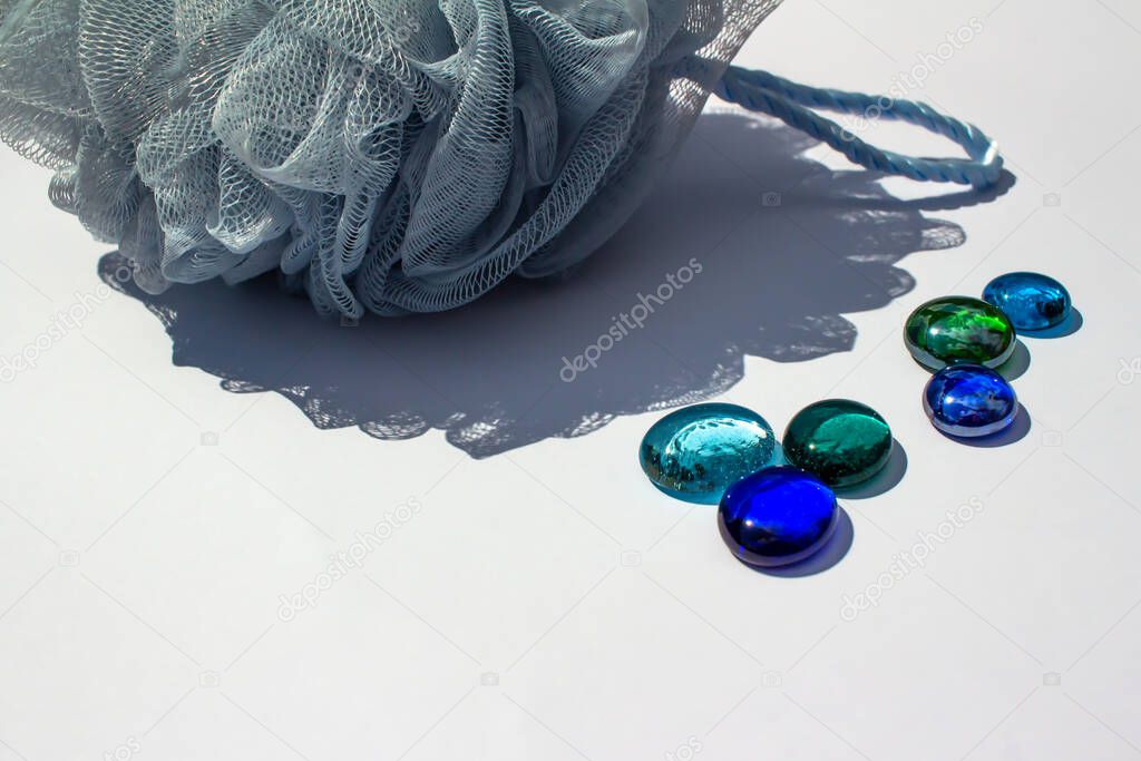Close up abstract view of colorful dragon tears and a blue mesh bath sponge on white background