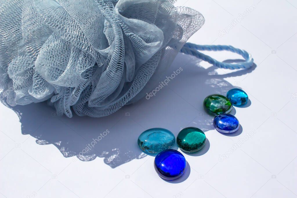 Close up abstract view of colorful dragon tears and a blue mesh bath sponge on white background
