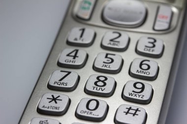 Gümüş renkli, kablosuz bir telefon ahizesi üzerindeki düğmelerin soyut doku görünümünü kapat