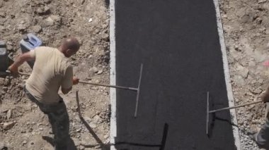 İşçiler asfalt kaldırım için çakıl döşüyorlar. Yol çalışmaları, sıkı çalışma, yakın çekim, yukarıdan görüş.