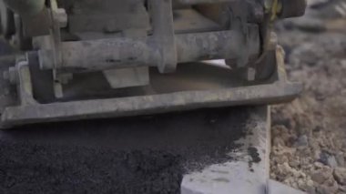 Kaldırımdaki titreşimli asfalt kaldırım makinesi. Yakın çekim. Yol çalışmaları, kaldırım onarımı, sıkı çalışma.