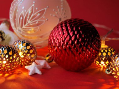 Kırmızı zemin üzerinde farklı Noel baloları, oyuncaklar ve fenerler, Noel ve yeni yıl kutlaması konsepti, Noel kartı. Yakın çekim, seçici odaklanma..