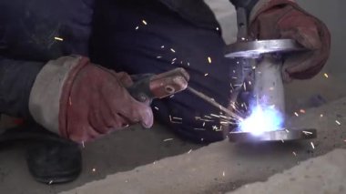 Üretim tesisinde yarı otomatik kaynak makinesinde elektrot ile çalışan kaynakçı. Kaynak kaynaklarından çıkan parlak kıvılcımlar.