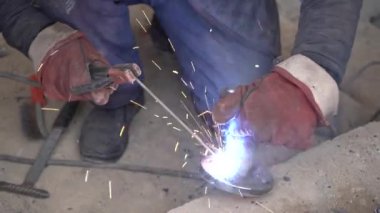 Üretim tesisinde yarı otomatik kaynak makinesinde elektrot ile çalışan kaynakçı. Kaynak kaynaklarından çıkan parlak kıvılcımlar.