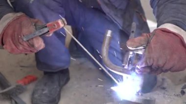 Üretim tesisinde yarı otomatik kaynak makinesinde elektrot ile çalışan kaynakçı. Kaynak kaynaklarından çıkan parlak kıvılcımlar.