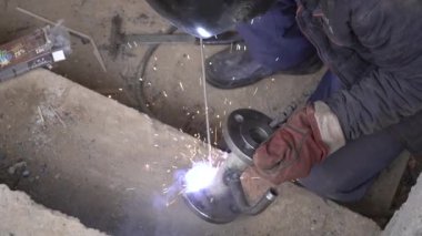 Üretim tesisinde yarı otomatik kaynak makinesinde elektrot ile çalışan kaynakçı. Kaynak kaynaklarından çıkan parlak kıvılcımlar.