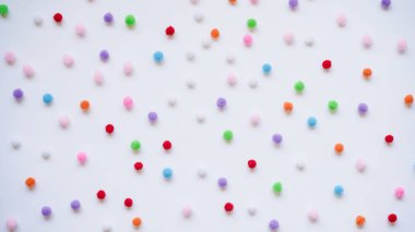 Beyaz arka planda, üst manzarada, düz bir zeminde birçok küçük renkli ponpon. Tatil için arka plan konsepti, mutlu yıllar..