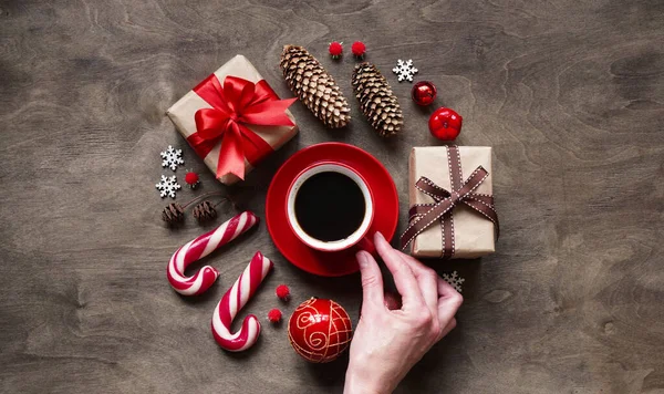 Christmas new year background,simple composition of christmas decoration gift boxes,red balls,cones,lollipops and red cup coffee on wooden background,flat lay,empty space for greeting text,copy spaes.