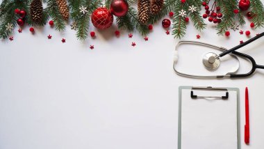 Beyaz arka planda noel bayrağı dalları, koniler, kırmızı toplar, kar taneleri, steteskop ve tablet. Kopyalama. Tıbbın yeni yılı.