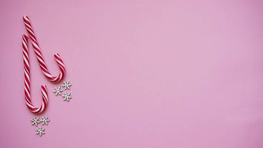 Noel lolipopu ve beyaz kar taneleri pembe arka plan, fotokopi alanı, üst manzara, düz alan. Noel ve yeni yıl dekorasyonu konsepti..