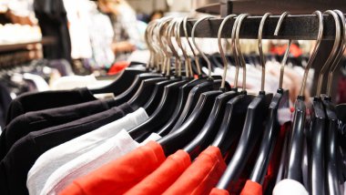 Modern moda kadın kıyafetleri bir giyim mağazasının mağazasındaki siyah plastik askılara asılıyor. İnternetten günlük kıyafet alışverişi. Seçici odak.