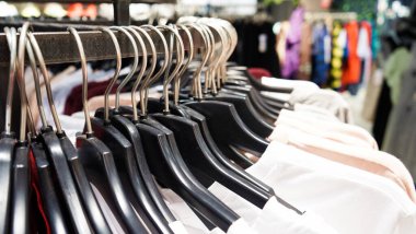 Modern moda kadın kıyafetleri bir giyim mağazasının mağazasındaki siyah plastik askılara asılıyor. İnternetten günlük kıyafet alışverişi. Seçici odak.