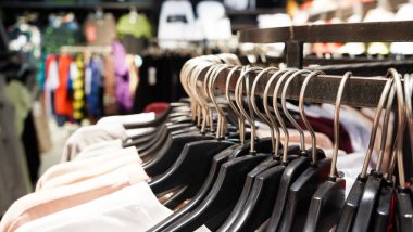Modern moda kadın kıyafetleri bir giyim mağazasının mağazasındaki siyah plastik askılara asılıyor. İnternetten günlük kıyafet alışverişi. Seçici odak.
