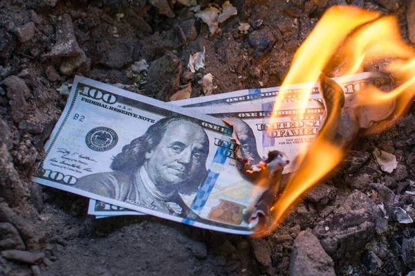 Three hundred dollar bills burn in the fire. Concept: recession, crisis, confusion, unhappiness, poverty. devaluation. Burning excess money. Excessive waste of money. Photo horizontal, close up