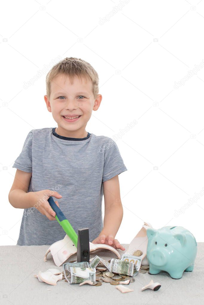 preschooler smashed his piggy bank with a hammer.There are coins and crumpled bills on the table.concept-the child is happy because he can buy what he has long dreamed of and for which he saved money.