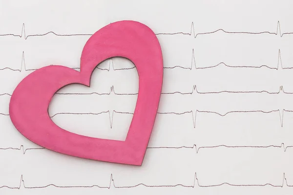 a red heart made of wood lies on a cardiogram. The concept is taking care of your health. horizontal photo, close-up