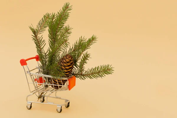 クリスマスツリーとコーンの枝があるカートの黄色の背景にクローズアップ コピースペースオンラインストアのコンセプト 製品の注文 新年2021 デザイン — ストック写真