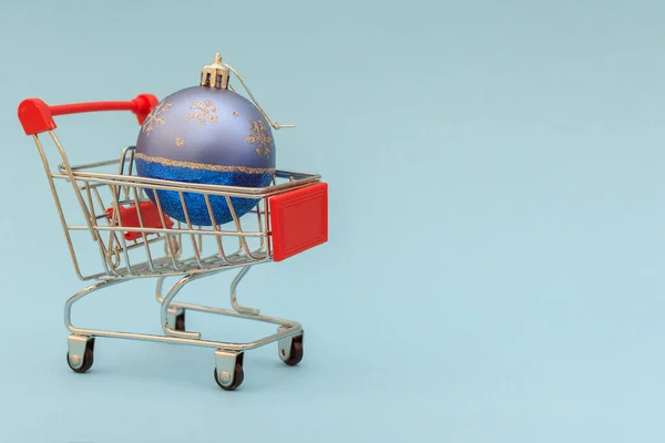 スーパーマーケットのカートに青いクリスマスボールがあります 水平写真 青の背景 アイデア クリスマスの準備 オンラインショッピング 自宅への商品の配達 — ストック写真