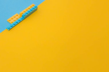 Sarı ve mavinin aksine, çapraz olarak, üzerinde sarı ve mavi renkli dört oyuncak yapı taşı var. Fikir - arkaplan, metin yeri, reklam