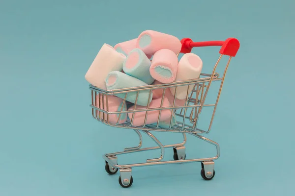 a mini supermarket cart filled with delicious marshmallows. Photo in pastel colors, close-up, horizontal. Idea - delivery of goods, purchase of goods, sweets, advertising.