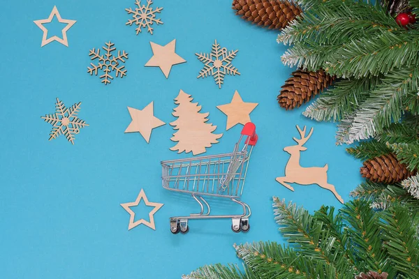 Mavi arka planda konili köknar dalları süpermarketten küçük bir tramvay ve kar taneleri, yıldızlar, bir geyik ve bir Noel ağacı şeklinde ahşap Noel oyuncakları. Fikir - ekolojik oyuncaklar satın alma.