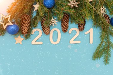 Mavi arka planda, kar taneleri ve balon şeklinde Noel süslemeleri olan ladin dalları var. 2021 rakamları. Fikir - bir tasarım şablonu, bir kartpostal, bir yılbaşı tebriği.