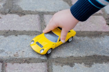 The childs hand leads a yellow toy car photo horizontal, close-up. clipart