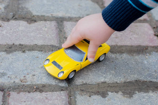 Childs 'ın eli sarı oyuncak arabanın fotoğrafını çekiyor. Yatay, yakın plan..