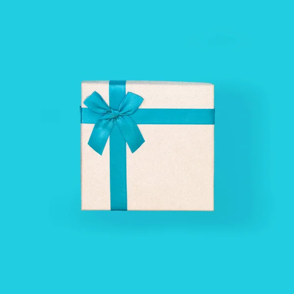 Caja de regalo blanca con una cinta azul y lazo, sobre un fondo azul. Vista superior, primer plano. Idea - diseño para el diseño, plantilla. —  Fotos de Stock