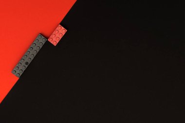 Yapıcının oyuncak yapı taşlarının üzerinde siyah ve kırmızı olarak çapraz yattığı siyah ve kırmızı zemin zıt. Fikir - arkaplan, metin yeri, reklam.