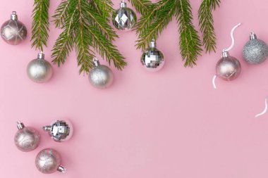 Yeni yıl ya da kış kompozisyonu, gerçek köknar dalları ve Noel topları pembe moda pastel arka planda, basit stil, üst görünüm, fotokopi alanı, bir kartpostal düzeni, tasarım şablonu.