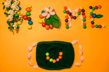 Evin yazılı olduğu turuncu arka planda gülümseyen bir maske.