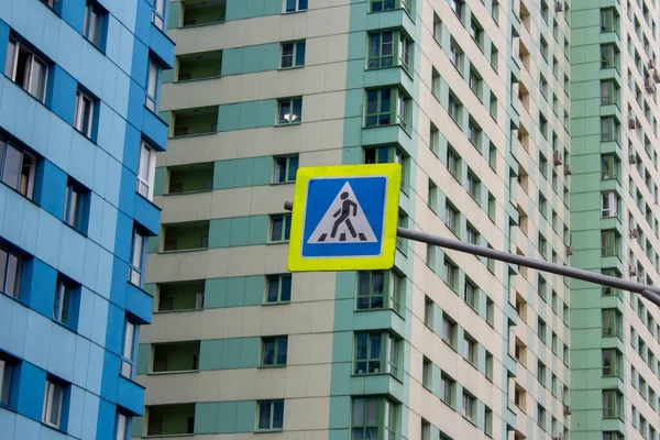Road sign of a pedestrian crossing against the background of multi-storey buildings. Road Markings and traffic Rules concept. Transport and motoring. Safety in the city. Urban habitat.