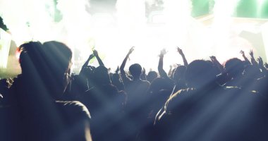 Arka görünümü parlak sahne ışıkları ellerini yükselterek festival kalabalık konser kalabalığa siluetleri, bulanık