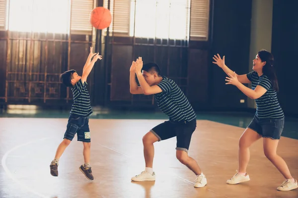Asyalı bir aile birlikte basketbol oynuyor. Mutlu aile tatilde birlikte vakit geçiriyor.