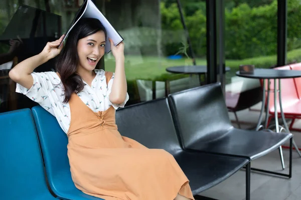 Kitap okuma ve gülümseyen Asyalı kadınlar ve başarılı bir ofiste çalıştıktan sonra bir kafede mutlu Relaxing.